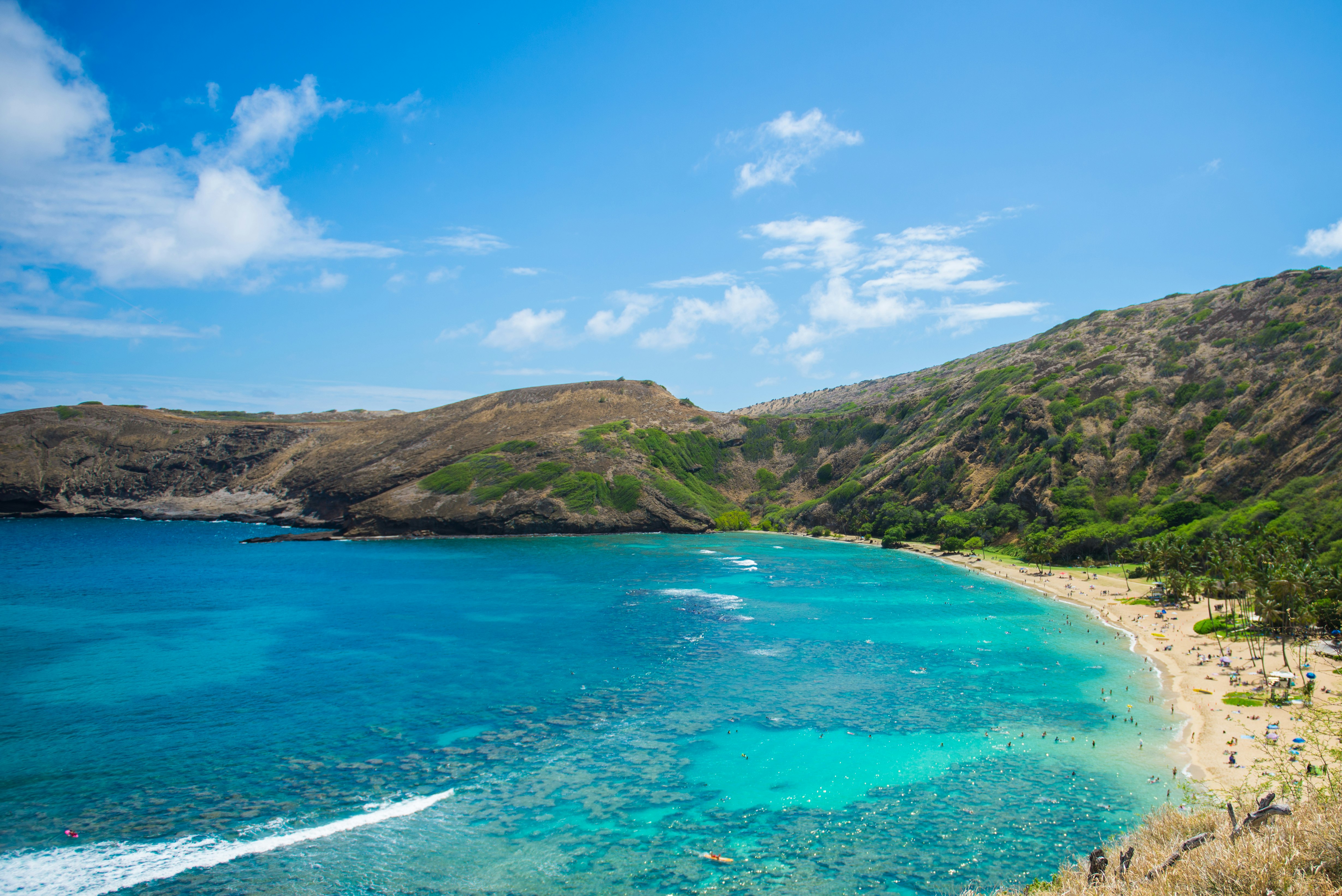 green mountain beside blue sea under blue sky during daytime